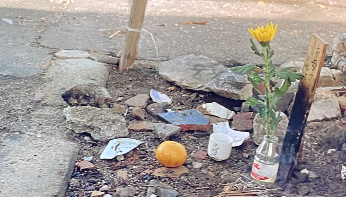 1995年公開の映画『男はつらいよ 第48作 紅の花』のワンシーン。阪神・淡路大震災で被災した神戸市長田区・菅原市場の道端に置かれた木の板に「お母さん、さようなら」と書かれたメッセージと花、線香が写る写真。