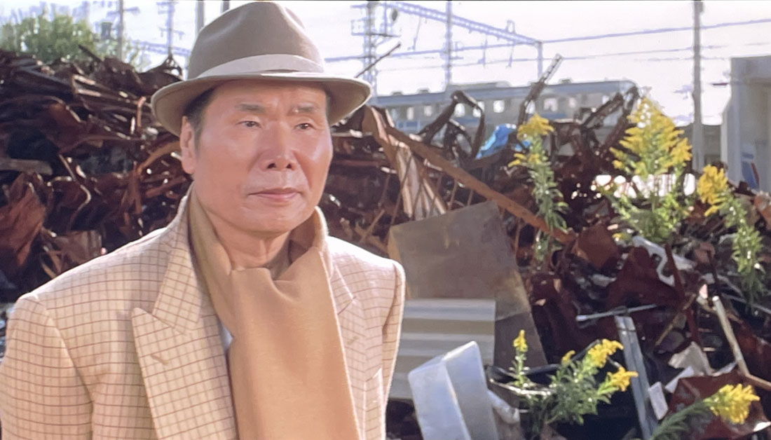 1995年公開の映画『男はつらいよ 第48作 紅の花』のワンシーン。寅次郎が阪神・淡路大震災直後の神戸市長田区・菅原市場に佇む様子を捉えた写真。