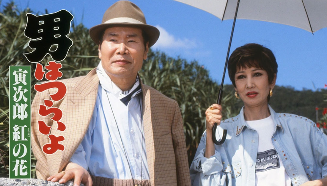 1995年公開の映画『男はつらいよ 第48作 寅次郎 紅の花』のワンシーン。渥美清さんと浅丘ルリ子さんが奄美大島の浜辺に立つ場面を捉えた写真。